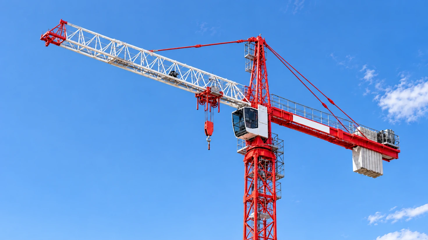 Red and white tower crane against a clear blue sky